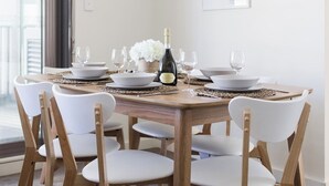 Een eetgedeelte met een houten tafel voor zes personen, omringd door witte stoelen.