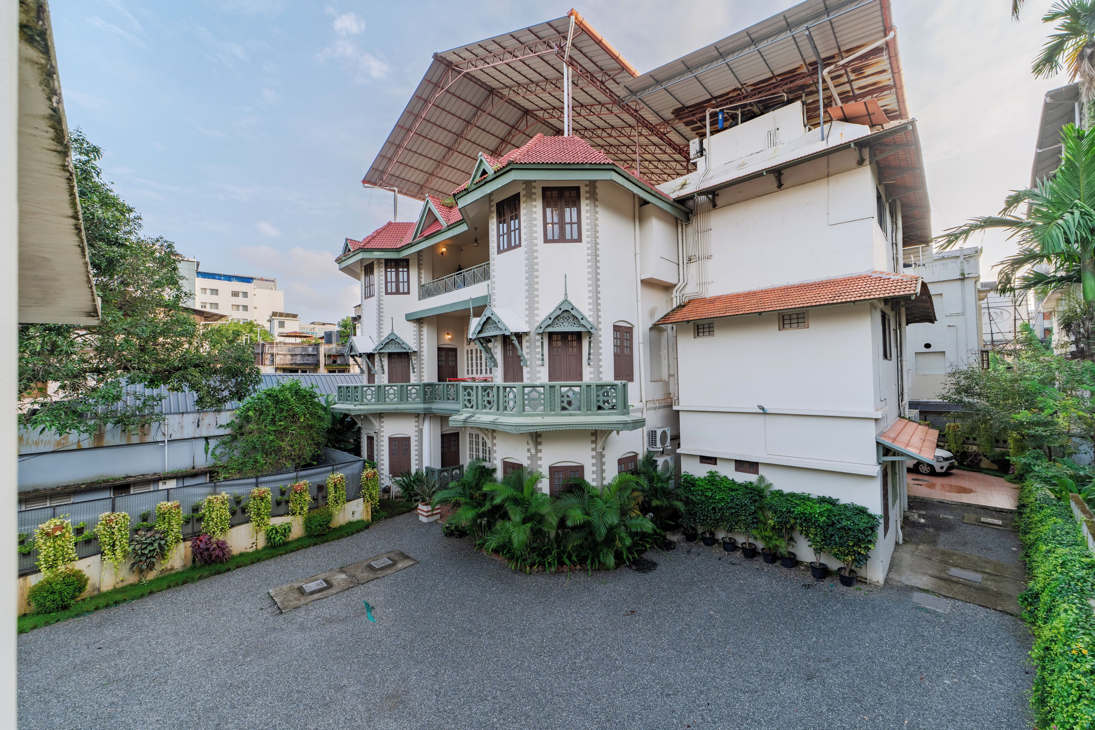 A multi-story building with a balcony, a covered walkway, and a garden area.