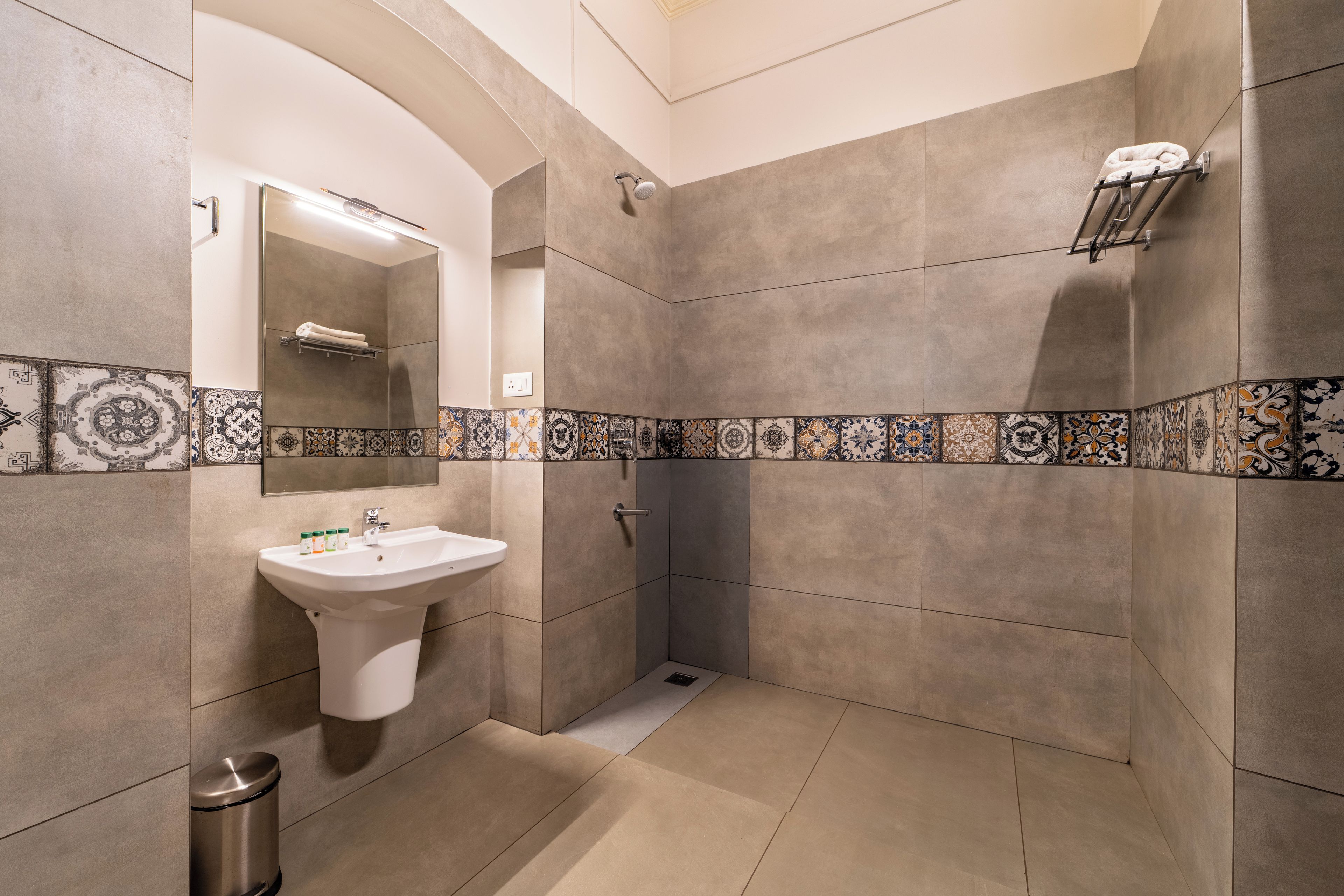 A bathroom with a sink, mirror, shower, and decorative tiles.