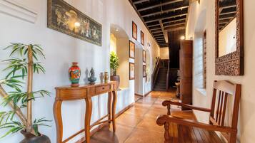 Un pasillo con un banco de madera, una mesa con adornos decorativos, una planta en maceta y cuadros en las paredes.