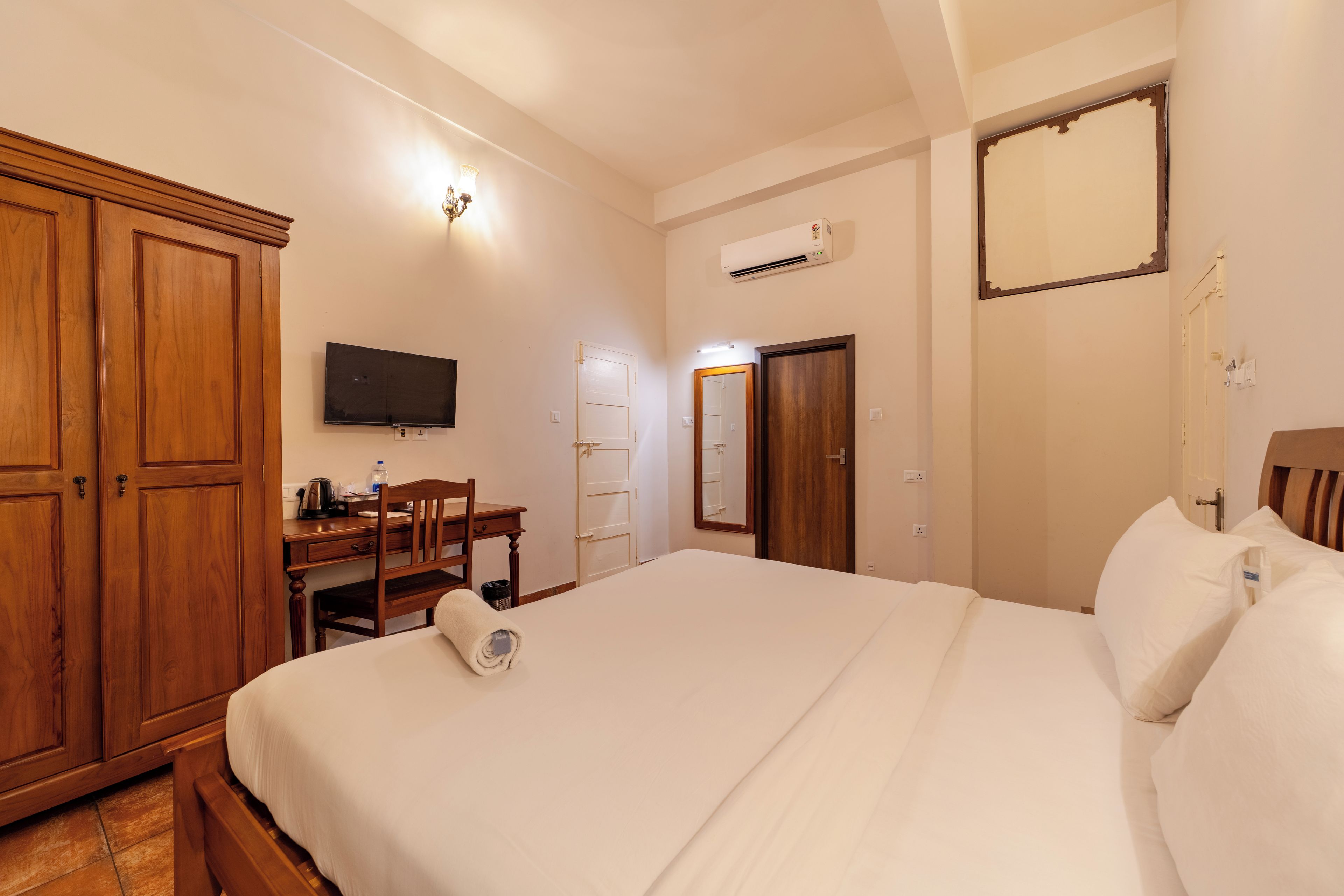 Une chambre d’hôtel comprenant un lit, un bureau avec une chaise, une télévision et une armoire.
