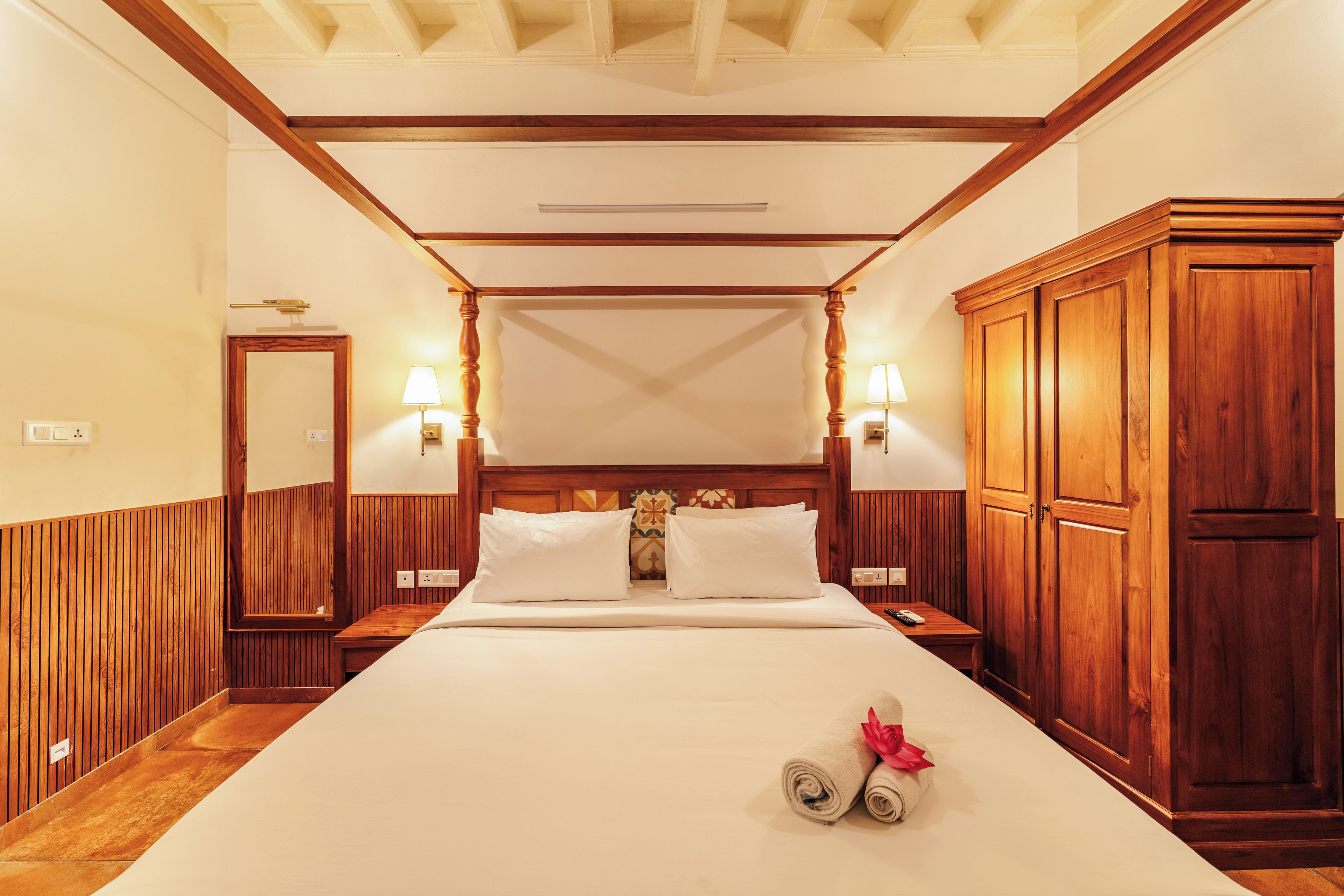 A hotel room with a large bed, wooden paneling, two bedside lamps, and a wardrobe.