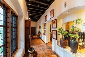 A hallway with a wooden door, a tiled floor, and framed pictures on the wall. - Sarada Mandiram A Heritage Hotel (Kanayannur)