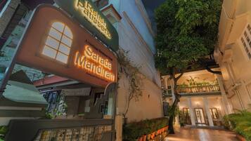 Une entrée d’hôtel avec une enseigne lumineuse, un portail et un chemin menant au bâtiment.
