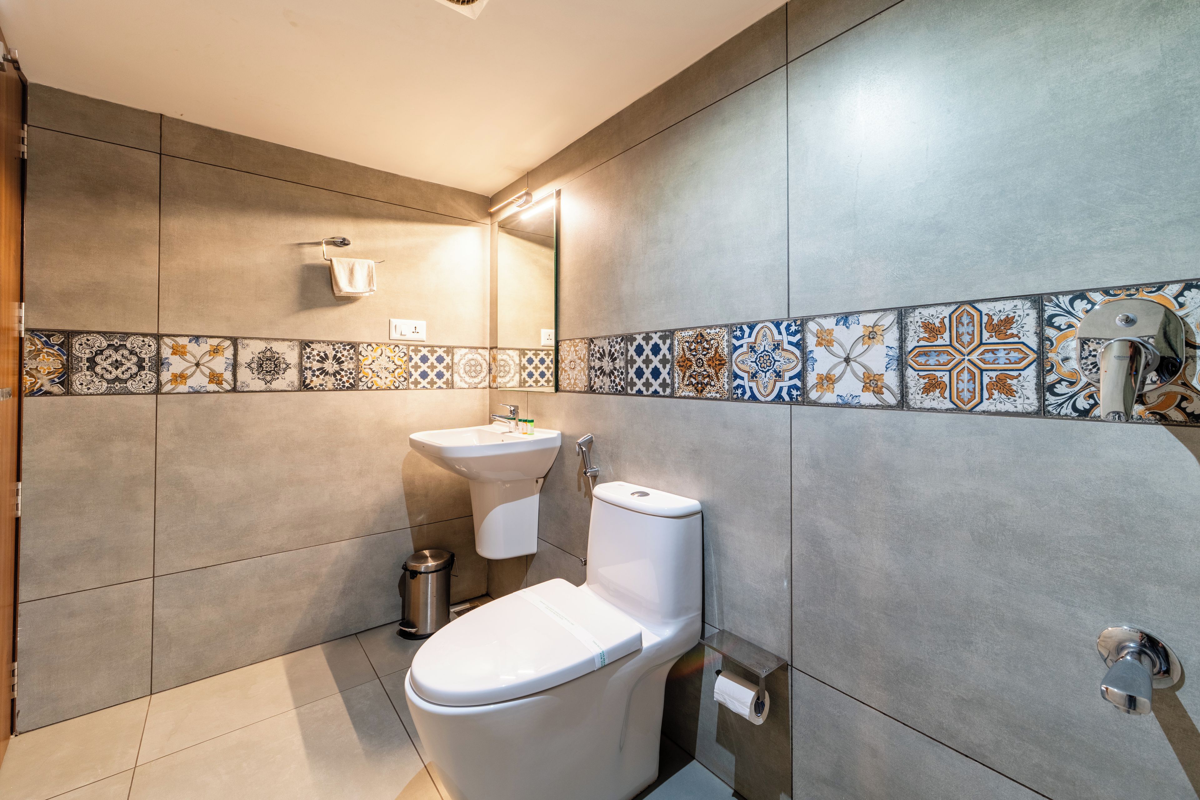 Un baño moderno con inodoro, lavamanos y cubo de basura.