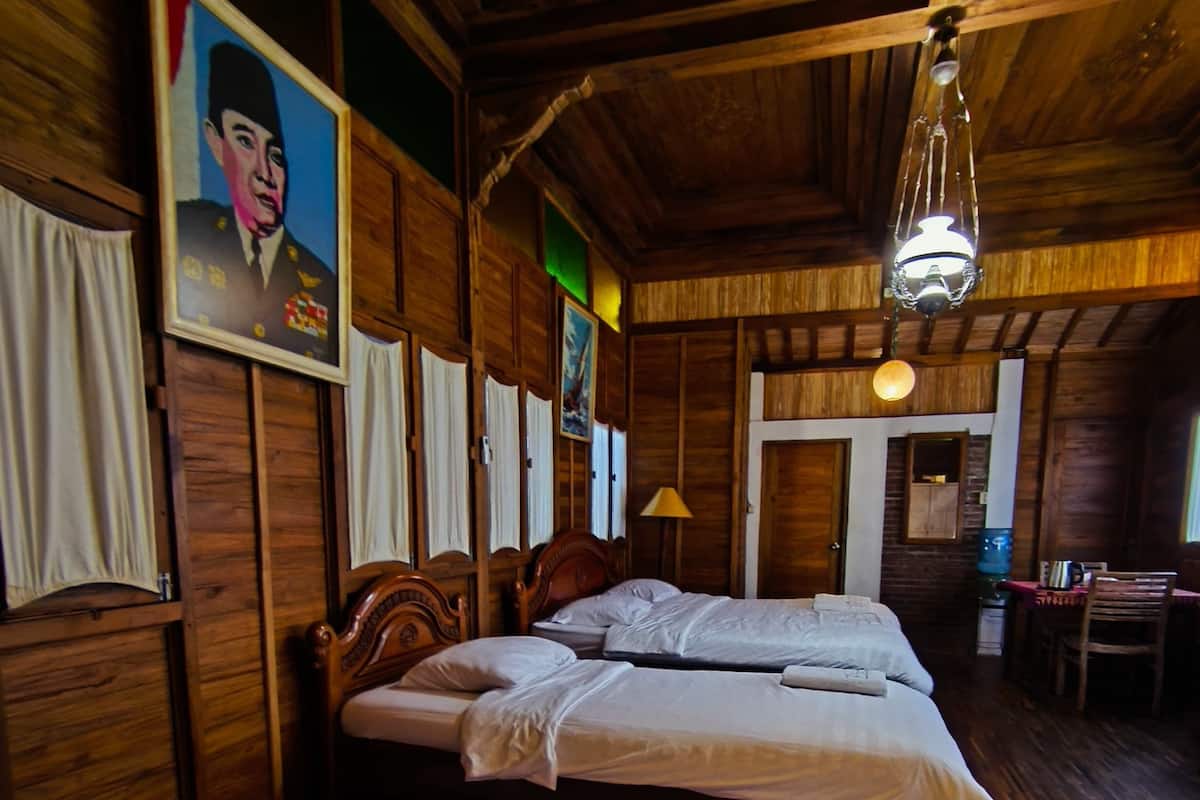 Um quarto de madeira com duas camas, teto de madeira e um quadro na parede.