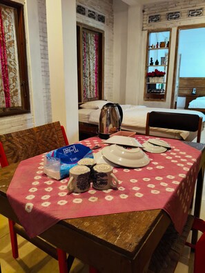A dining area with a table set for two, a kettle, and a bag of bread. - The Sarimbit Heritage Villa Yogyakarta (Yogyakarta)