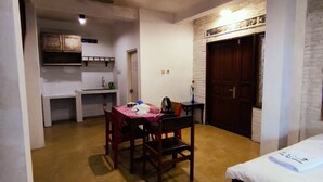 Una stanza compatta con tavolo e sedie, un letto e un angolo cottura sullo sfondo.