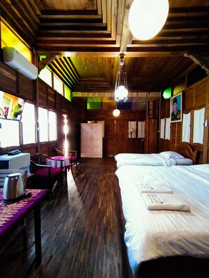 A wooden room with a bed, a table, and a TV. - The Sarimbit Heritage Villa Yogyakarta (Yogyakarta)