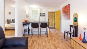 A compact living space with a kitchenette, a dining area with three chairs, a sofa, and a small table with decorative items.
