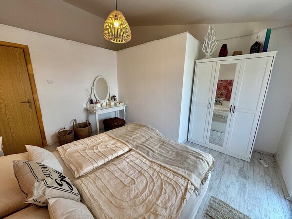 A bedroom with a bed, a dresser, a mirror, and a hanging light fixture. - Apartment Evelyn (Jadranovo)
