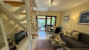 Ein modernes Wohnzimmer mit einem Glastisch, einer Couch, einem Fernseher und einer Treppe.