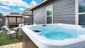 En trädgård med en bubbelpool, ett trädäck, ett utemöblemang och en gräsmatta.