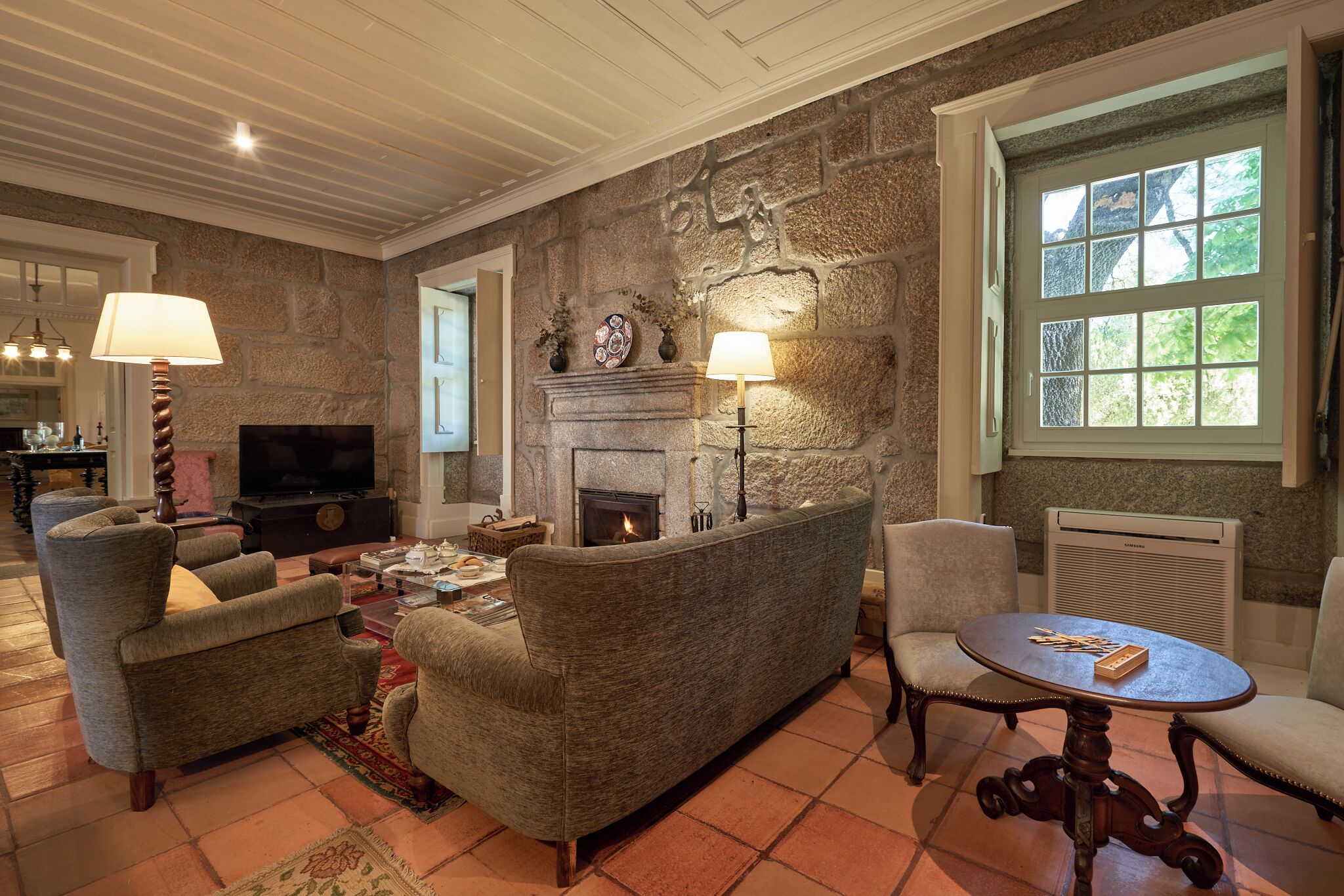 A living room with a stone fireplace, a television, and a dining table with chairs.