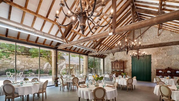 A spacious dining area with round tables and chairs, large windows, and a rustic wooden ceiling. - Solar de Vilar Seco (Nelas)