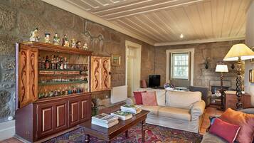 A cozy living room with a fireplace, a wooden cabinet with bottles, a sofa, and a coffee table.