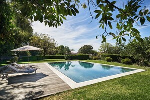 Una piscina al aire libre de temporada, sombrillas