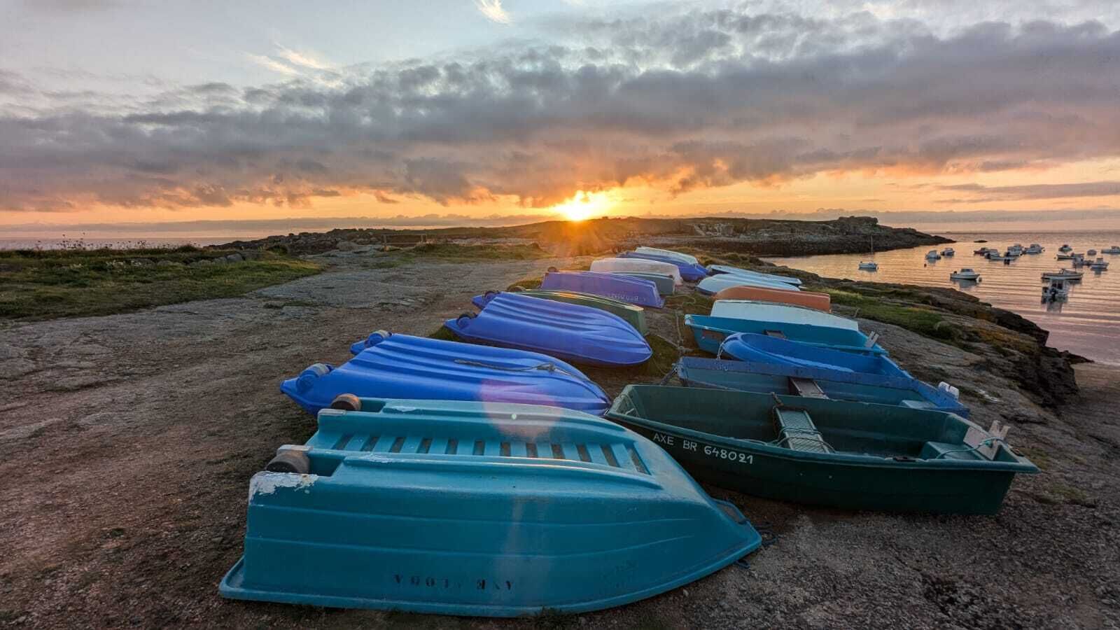 Une rangée de bateaux était alignée sur une côte rocheuse, avec un coucher de soleil en arrière-plan.