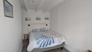 Una camera da letto con un letto, uno sgabello e tre quadri appesi al muro.