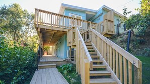 A wooden staircase leading to a blue building with a balcony.