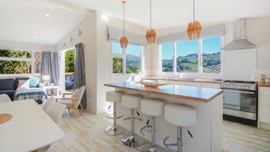 A modern kitchen with a central island, bar stools, and a view of the countryside.
