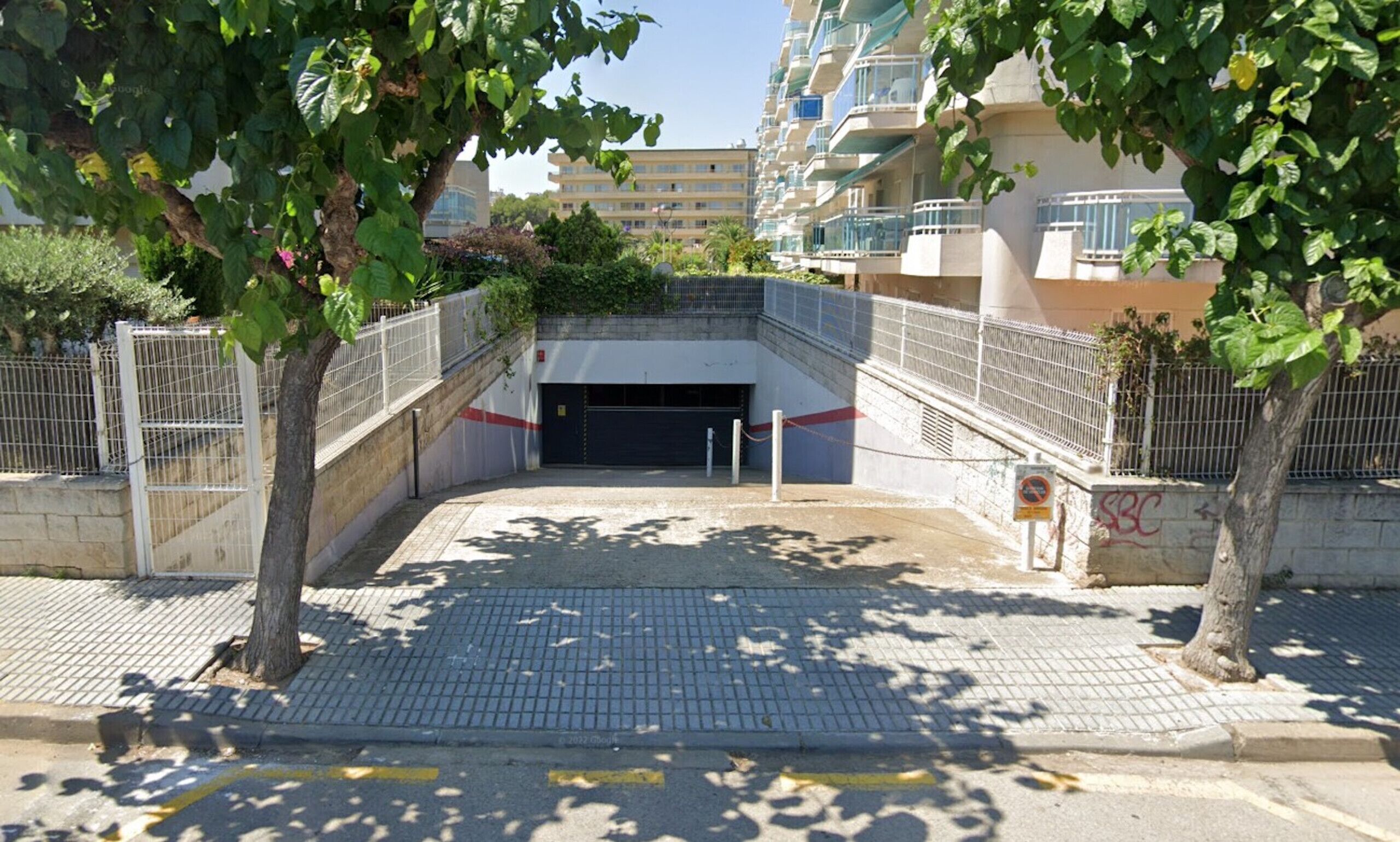 A gated entrance to a building with a covered walkway leading to a garage.