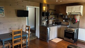 Una cocina compacta con armarios de madera, cocina a gas, microondas y un lavamanos.