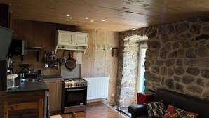 Una cocina acogedora con paredes de madera, una pared de piedra y una chimenea de piedra.