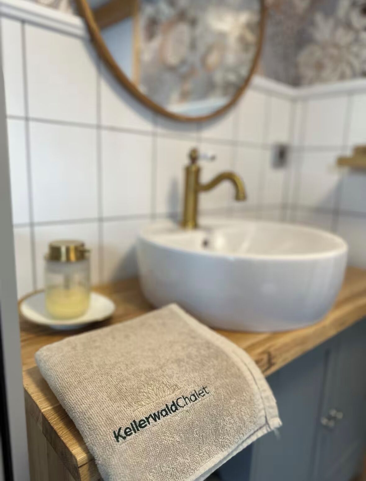 A bathroom with a white sink, a gold faucet, and a towel with text on it.