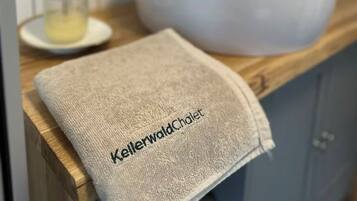 A bathroom with a white sink, a gold faucet, and a towel with text on it.