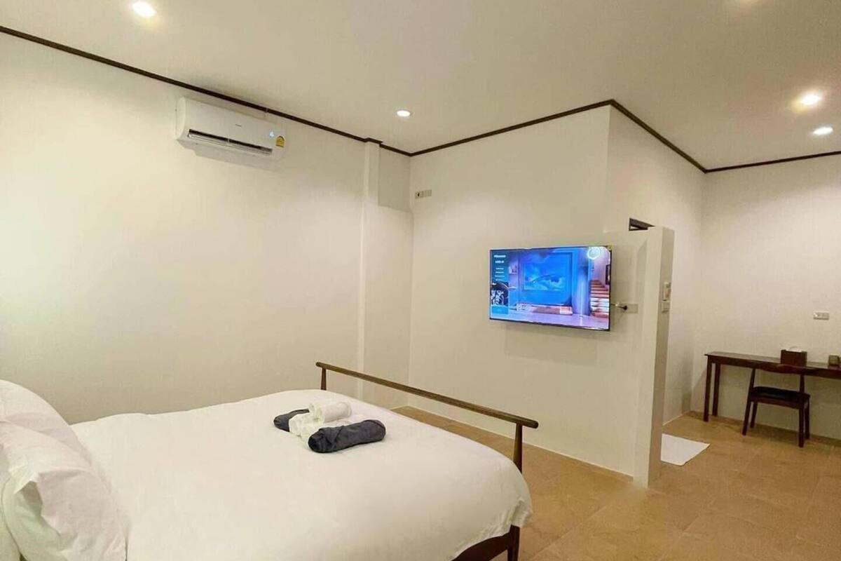 A hotel room with a bed, a flat-screen TV mounted on the wall, and a desk with a chair.