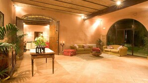 A cozy living room with a wooden table, two sofas, and a large arched window. - My Rental Homes - Villa dei Cappuccini with private pool, jacuzzi, air conditioning (Gubbio)