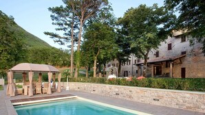 A pool area with a gazebo, stone walls, and a building with a tiled roof. - My Rental Homes - Villa dei Cappuccini with private pool, jacuzzi, air conditioning (Gubbio)