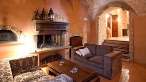 A cozy interior with a stone fireplace, a sofa, and a wooden coffee table. - My Rental Homes - Villa dei Cappuccini with private pool, jacuzzi, air conditioning (Gubbio)