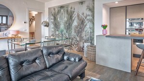 Een moderne woonkamer met een leren bank, een glazen eettafel en een keuken met een inbouw kookeiland.