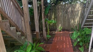 Ein roter Weg in einer Gartenanlage mit Holzbauten und Grünpflanzen.