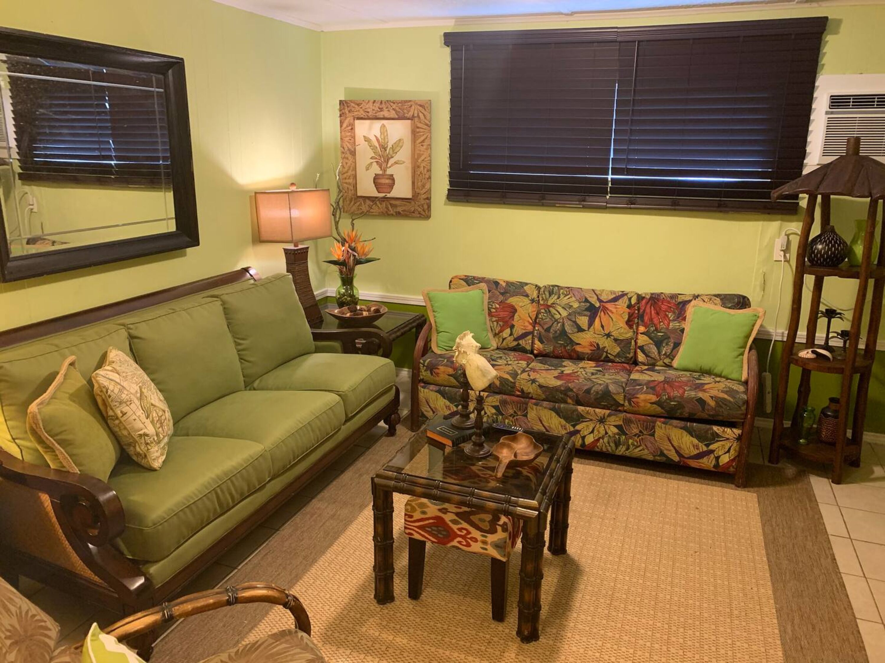 A living room with a green sofa, a patterned sofa, a small table, and a chair.