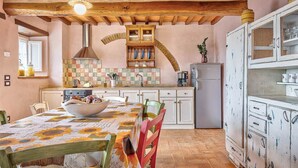 Eine rustikale Küche mit freiliegenden Holzbalken, einer gefliesten Spritzschutzwand und einem alten Kühlschrank.