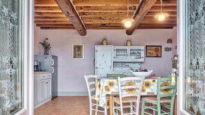 Eine rustikale Küche mit Holzbalkendecke, einem Tisch mit Sonnenblumen-Tischdecken und alten Schränken.