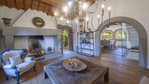 Ein geräumiges Wohnzimmer mit Kamin, Holzmöbeln und einer Chandelier.