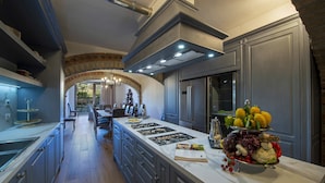 A modern kitchen with a marble countertop, stainless steel appliances, and a central island with a fruit display. - Villa Serena with private pool - My Rental Homes (Greve In Chianti)
