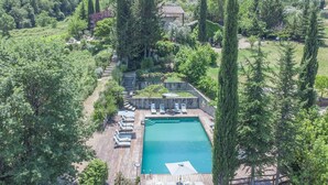A large rectangular swimming pool surrounded by a wooden deck with lounge chairs and umbrellas. - Villa Grevigiana pool and SPA - My Rental Homes (Greve In Chianti)