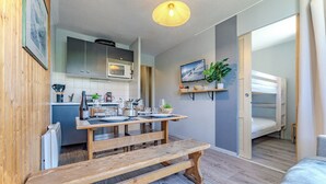 Une cuisine compacte équipée d’un four à micro-ondes, d’une table à manger pour quatre personnes et d’un banc.
