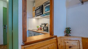 Une cuisine avec des meubles en bois, un four à micro-ondes et un petit sapin de Noël.