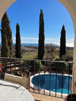 Piscina com vista para o mar e árvores altas.
