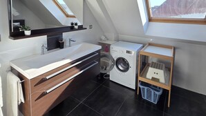 Un bagno moderno con una finestra sul tetto, una lavatrice e un mobile bagno in legno.