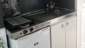 Een compacte keuken met een inbouwmagnetron, een broodrooster en een kleine koelkast.