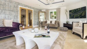 A spacious living room with a white table, two sofas, and a large window. - Poole Brae Lake View Getaway | Ridgestone (Bowness-on-Windermere)
