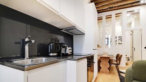 Eine moderne Küche mit Spüle aus Edelstahl, einer schwarzen Kaffeemaschine und einem Einbauofen.