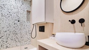 Un baño moderno con lavamanos blanco, inodoro y salpicadero con motas.